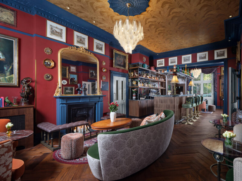 Ottie's salon at bertrand's townhouse with large green sofa, burgundy and blue walls