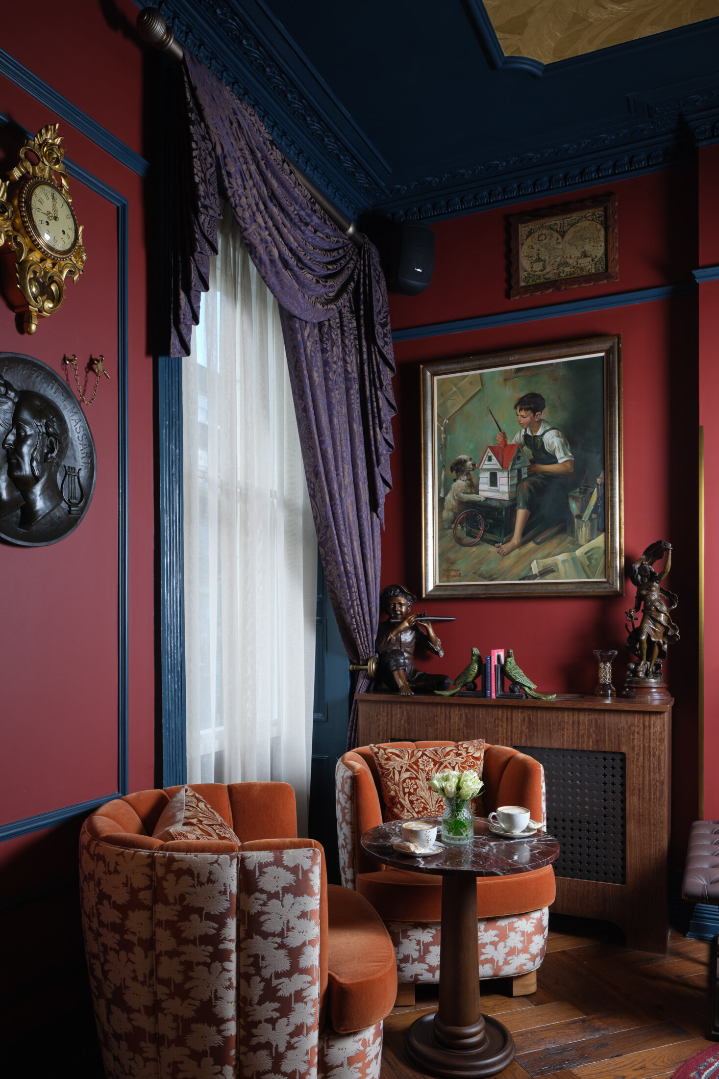 Ottie's salon at bertrand's townhouse with ornate clocks, and orange tub chairs
