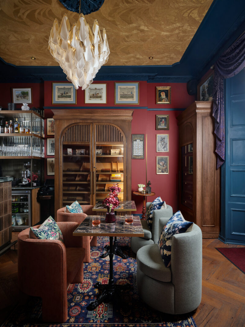 ottie's salon at bertrand's townhouse with large chairs, glasses of whiskey and the cigar cabinet