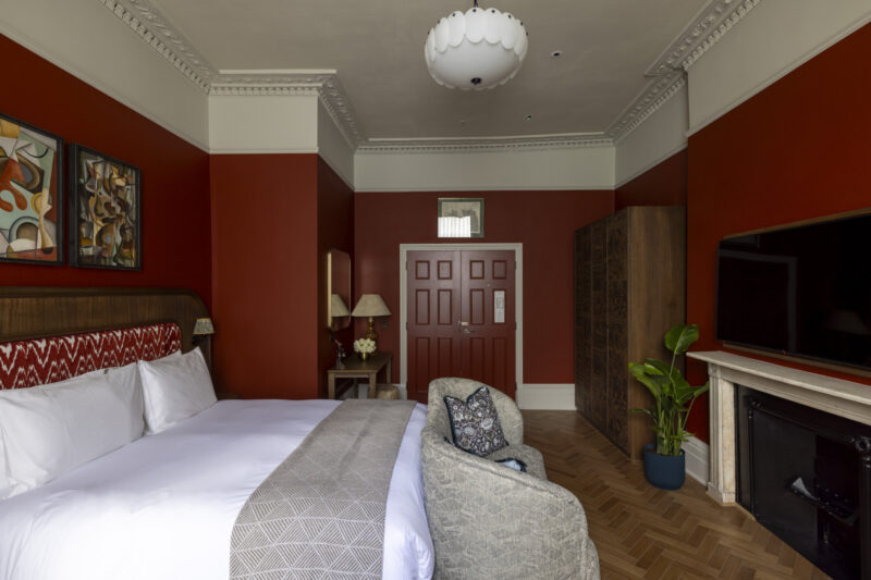 large hotel bedroom with red walls and doors