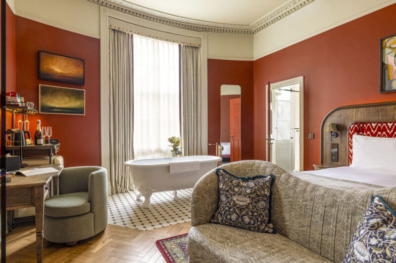 hotel suite with large free standing roll top bathtub and red walls