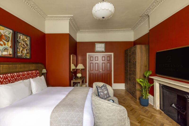 large hotel bedroom with dark red doors and walls