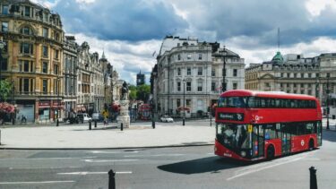A road in Central London on a cloudy day, with historic buildings and a red bus.