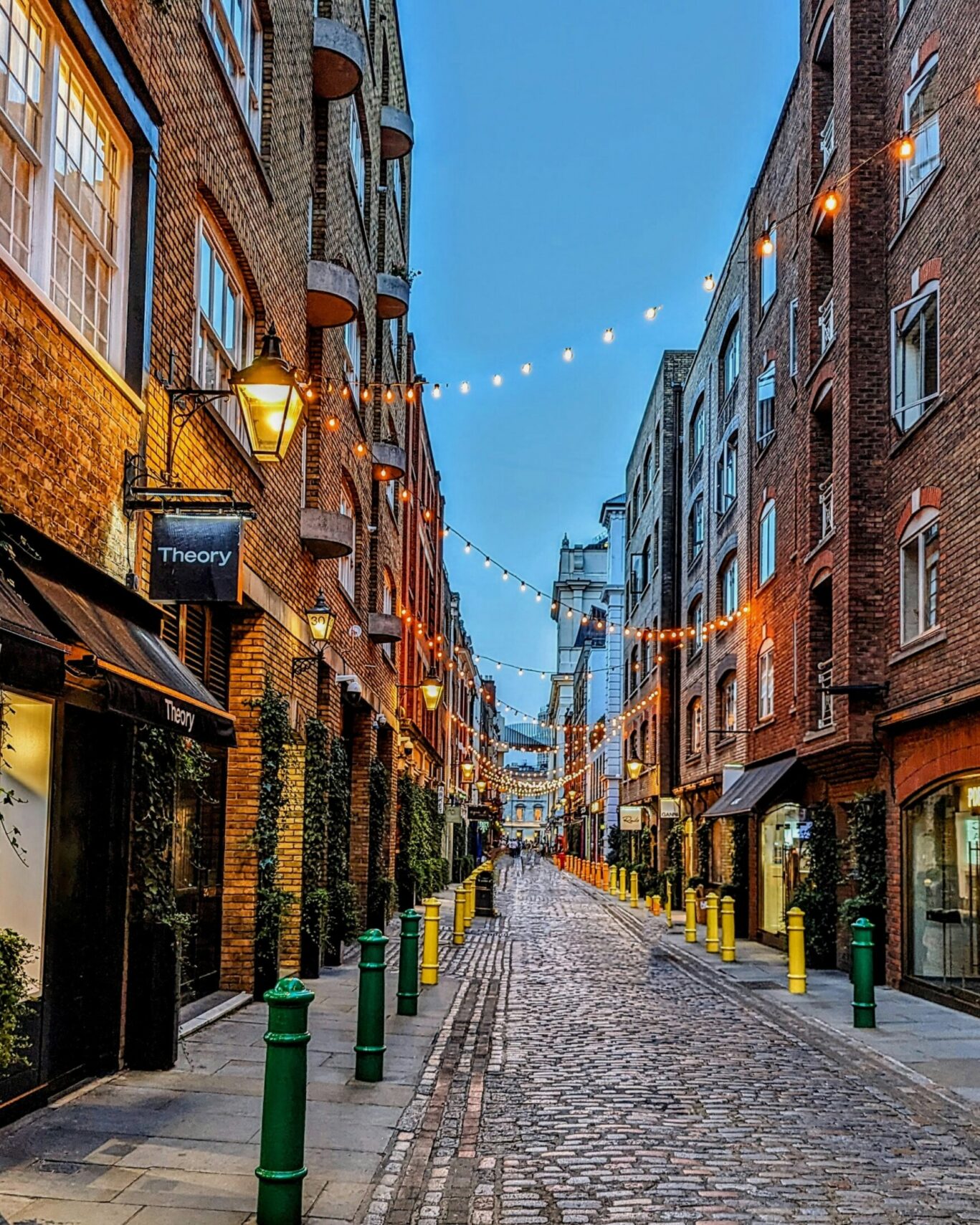 A street of Covent Garden at dusk, with fairy lights hanging through.