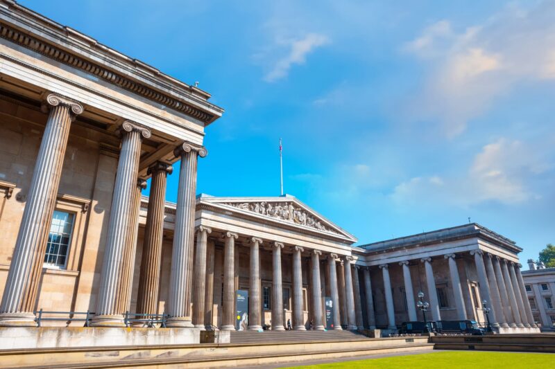 The British Museum building on a bright sunny day, with several tall pillars decorating the entrance.
