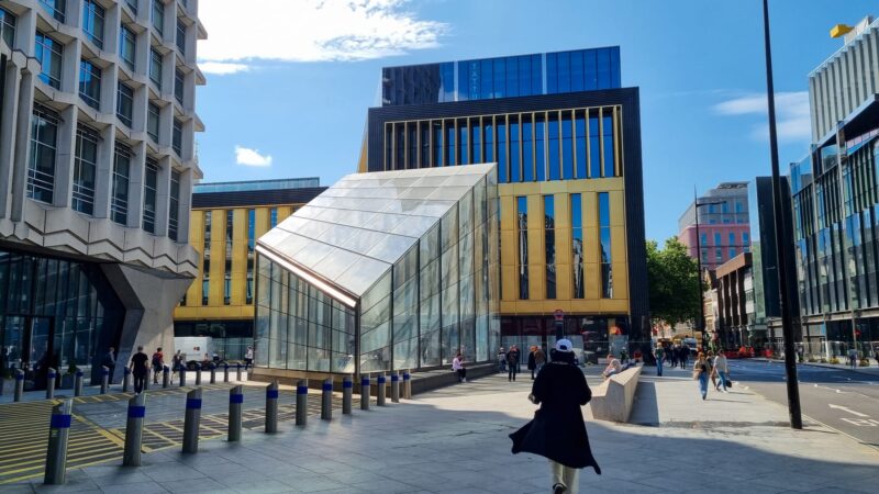 Tottenham Court Road on a bright, sunny day with wispy clouds.