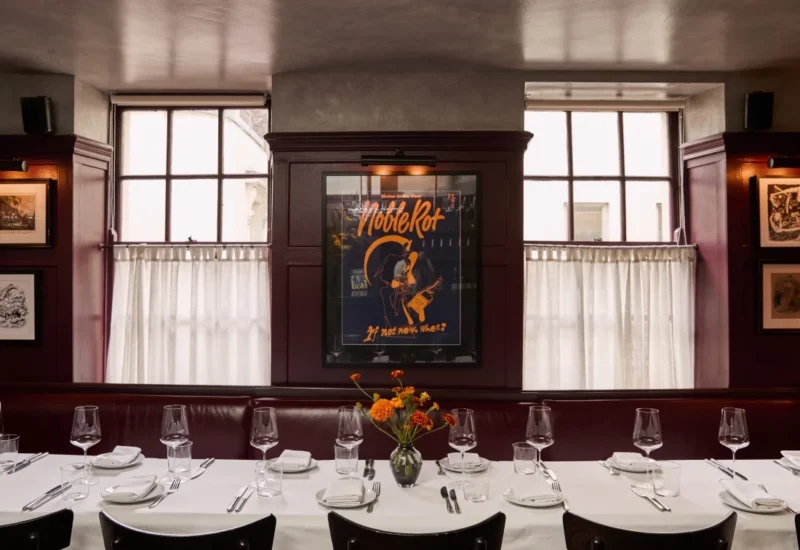 A long dining table set up with wine glasses, cutlery and plates. Inside Noble Rot